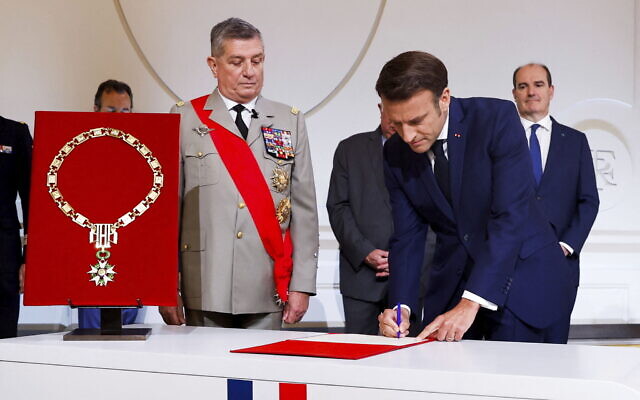 France's Military Chief of Staff to the presidency Benoit Puga, center, left, stands next to French President Emmanuel Macron signing a document during the ceremony of his inauguration for a second term at the Elysee palace, in Paris, France, Saturday, May 7, 2022.  (Gonzalo Fuentes/Pool via AP)