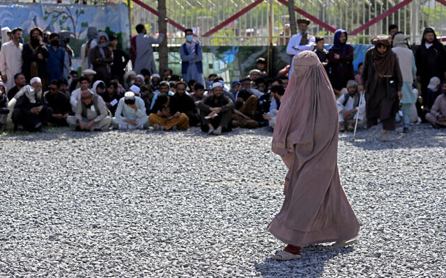 An Afghan woman waits to receives food rations distributed by a Saudi humanitarian aid group, in Kabul, Afghanistan, on Monday, April 25, 2022. (AP Photo/Ebrahim Noroozi)