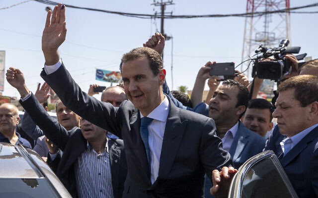 Syrian President Bashar Assad, center, waves to his supporters at a polling station during the Presidential elections in the town of Douma, in the eastern Ghouta region, near the Syrian capital Damascus, Syria, May 26, 2021. (AP Photo/Hassan Ammar, file)