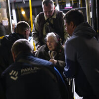 A woman who fled from the Azovstal steel plant in Mariupol is helped from a bus upon her arrival at a reception center for displaced people in Zaporizhzhia, Ukraine, on May 8, 2022. (Francisco Seco/AP)