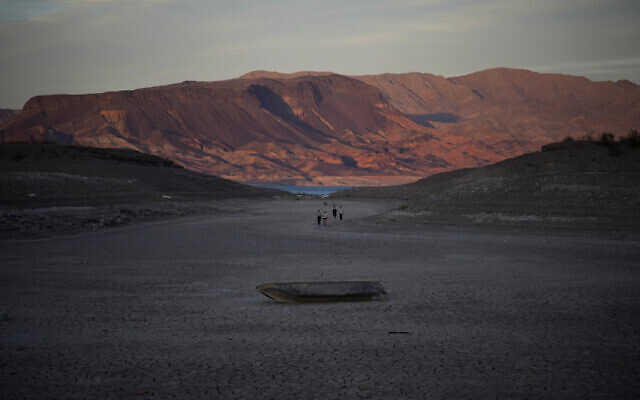 A formally sunken boat sits on cracked earth hundreds of feet from what is now the shoreline on Lake Mead at the Lake Mead National Recreation Area, May 9, 2022, near Boulder City, Nevada  (AP Photo/John Locher)