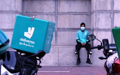A food-delivery worker for Deliveroo takes a moment as he returns to work in Dubai, United Arab Emirates, May 2, 2022. (Isabel Debre/AP)