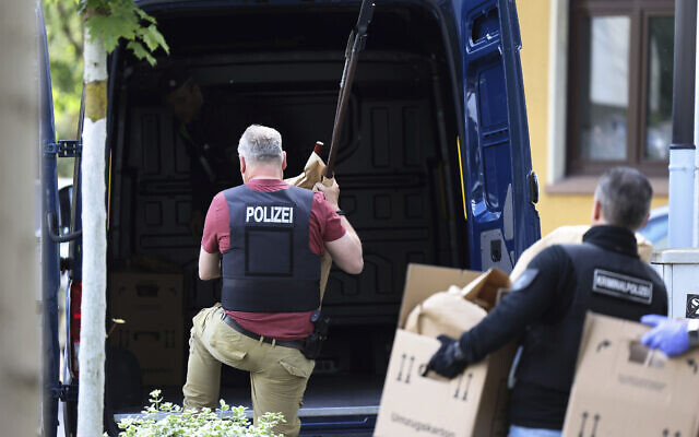 Police officers carry objects, including several stabbing weapons and spears, from the suspect's home in Essen, Germany, May 12, 2022. (David Young/dpa via AP)