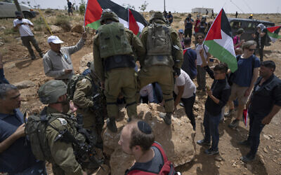 Israeli troops prevent Palestinian, Israeli and foreign peace activists from moving a rock that is blocking a road that passes close to the Israeli Jewish settlement of Mitzpe Yair, Masafer Yatta, West Bank، Friday, May 13, 2022. (AP/Nasser Nasser)