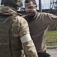 In this photo taken from a video released by the Russian Defense Ministry Press Service on May 18, 2022, a Russian serviceman frisks a Ukrainian soldier after he left the besieged Azovstal steel plant in Mariupol, Ukraine. (Russian Defense Ministry Press Service via AP)