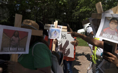 Protesters carry crosses with photos of victims of the Robb Elementary School shooting in Uvalde, Texas, as they demonstrate outside the George R. Brown Convention Center where the National Rifle Association's annual meeting is held in Houston, May 27, 2022. (AP Photo/Jae C. Hong)
