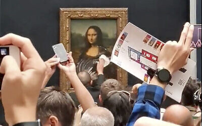 A security guard cleans smeared cream from the glass protecting the Mona Lisa at the Louvre Museum, in Paris, France, May 29, 2022. (@Klevisl007 via AP)