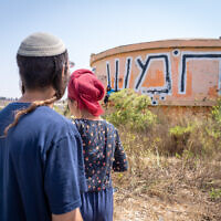 Illustrative: Visitors walk by the water tower on the ruins of the evacuated settlement of Homesh on August 27, 2019. (Hillel Maeir/Flash90)