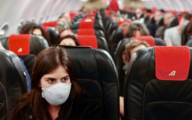 A woman wears a face mask on a flight from Ben Gurion International Airport to Rome on February 21, 2020. (Nati shohat/Flash90)