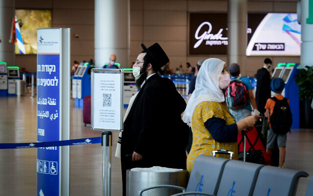 Travelers wearing protective face masks at Ben Gurion Airport, on August 5, 2021. (Avshalom Sassoni/Flash90)