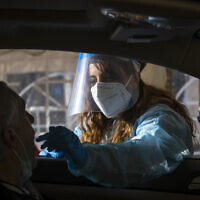 A Magen David Adom health worker take a swab sample from at a drive-thru COVID-19 testing complex in Jerusalem, on March 22, 2022. (Olivier Fitoussi/Flash90)