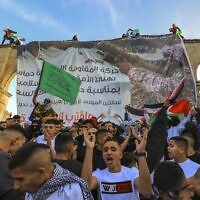 Palestinians chant pro-Hamas slogans following Eid al-Fitr prayers in front of a banner supporting the terror group at the Al-Aqsa Mosque atop the Temple Mount in Jerusalem on May 2, 2022. (Jamal Awad/Flash90