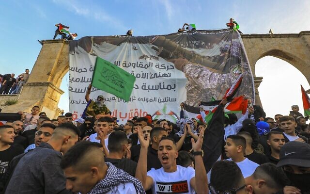 Palestinians chant pro-Hamas slogans following Eid al-Fitr prayers in front of a banner supporting the terror group at the Al-Aqsa Mosque atop the Temple Mount in Jerusalem on May 2, 2022. Photo by Jamal Awad/Flash90