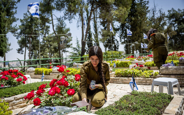 Israeli soldiers put flowers and candles on graves of fallen soldiers in Mount Herzl Military Cemetery in Jerusalem, on May 3, 2022, ahead of Israeli Memorial Day, May 4, 2022. (Yonatan Sindel/Flash90)