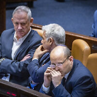 Defense Minister Benny Gantz, left,  Foreign Minister Yair Lapid, center, and Prime Minister Naftali Bennett attend a plenum session in the assembly hall of the Knesset, on May 16, 2022. (Olivier Fitoussi/FLASH90)