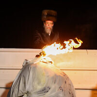 The head of the Boyan Hasidic sect lights a bonfire during Lag B'Omer celebrations on Mount Meron in northern Israel on May 18, 2022. (David Cohen/Flash90)