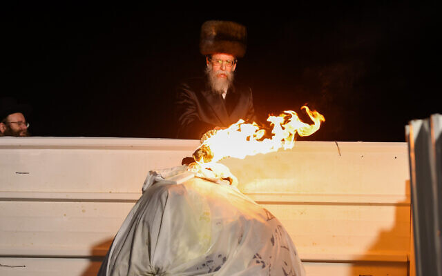 The head of the Boyan Hasidic sect lights a bonfire during Lag B'Omer celebrations on Mount Meron in northern Israel on May 18, 2022. (David Cohen/Flash90)