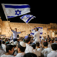 Jewish men dance with Israeli flags at the Western Wall in Jerusalem Old City on the eve of Jerusalem Day, May 28, 2022. (Noam Revkin Fenton/Flash90)