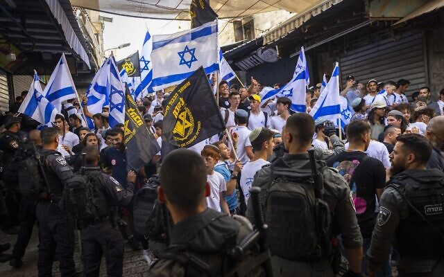 Members of the far-right, anti-miscegenation group Lehava wave the organization's flag alongside Israeli flags during a march through the Muslim Quarter of Jerusalem's Old City as part of Jerusalem Day on May 29, 2022. (Olivier Fitoussi/Flash90)