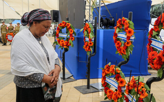 A woman cries in front of wreaths during a ceremony honoring the thousands of Ethiopian Jews who died en route to Israel from 1979 to 1990, at Jerusalem's Mount Herzl cemetery on May 29, 2022. (Marc Israel Sellem/Pool)