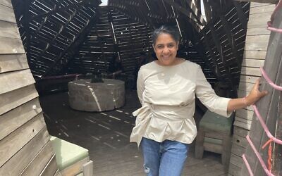 Visiting Indian artist Vibha Galhotra, at the entrance of the wooden meditation temple at Jerusalem's Muslala, with the stone altar in back of her, at its center, created as part of her 10-week residency in the Jerusalem International Fellows, through May 2022 (Jessica Steinberg/Times of Israel)