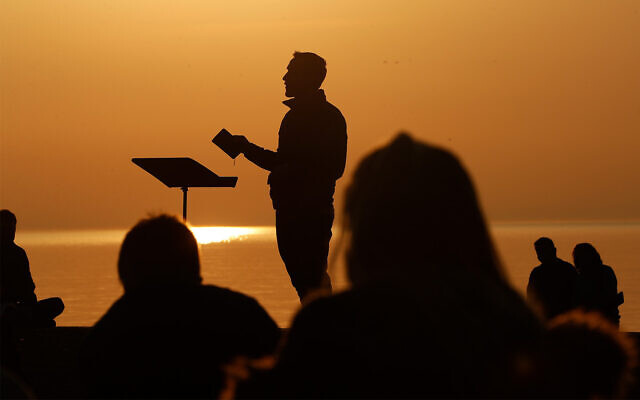 Park Community Church Associate Pastor Trevor Lovell is silhouetted against the sky as he leads an Easter sunrise service while parishioners listen on Sunday, April 4, 2021, at North Avenue Beach in Chicago. (AP Photo/Shafkat Anowar, File)