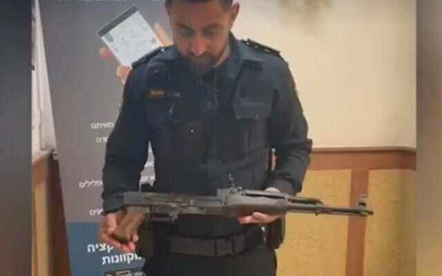 An officer holds an AK-type rifle that was found in the Sea of Galilee, May 28, 2022, (Screenshot: Ynet)