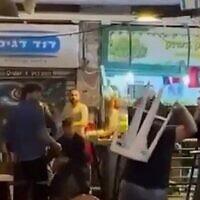 People fighting at Jerusalem's Mahane Yehuda market with chairs and tables, May 15, 2022. (screenshot).