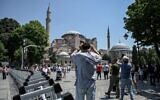 Tourists take pictures of the Hagia Sophia Mosque while standing next to a police fence in Istanbul, on June 14, 2022. (Ozan Kose/AFP)