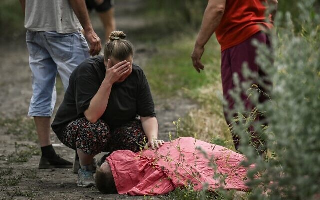 A woman mourns over the body of her relative who was reportedly killed by a cluster rocket in the city of Lysychansk in the eastern Ukrainian region of Donbas on June 18, 2022 amid the Russian invasion of the country. (ARIS MESSINIS / AFP)