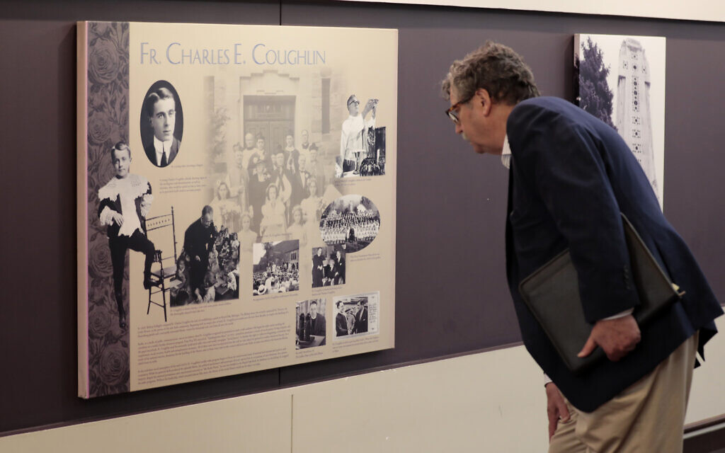 Levi Smith looks at a plaque for Father Charles Coughlin in the lobby of the Shrine of the Little Flower in Royal Oak, Michigan, May 31, 2022, before a 'discussion of the Jewish-Catholic relationship.' The event was co-sponsored by the Detroit JCRC/AJC and the Archdiocese of Detroit. The Shrine was founded by Father Coughlin, who had an antisemitic radio show in the 1930s. (Photo by Jeff Kowalsky for JTA)
