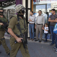 Illustrative: Israeli soldiers walk though a Hebron market on June 19, 2014. (AP/Majdi Mohammed)