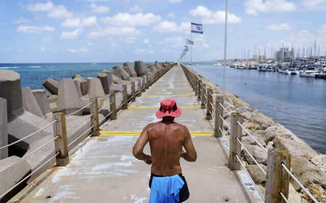A jogger runs along a marina in Herzliya, Israel, June 2, 2021. (AP Photo/David Goldman)