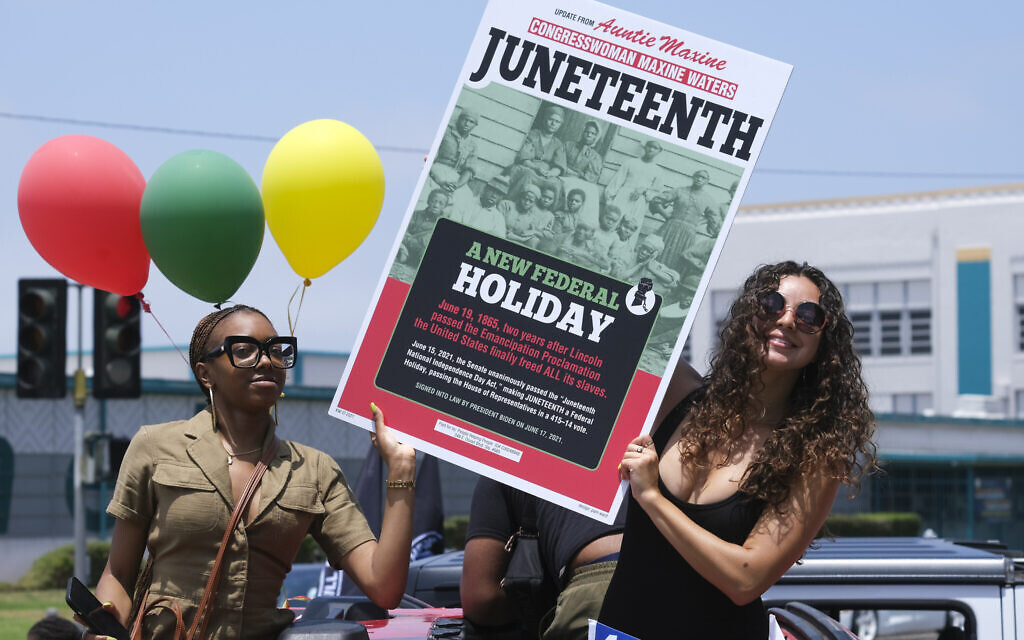 People hold a sign in their car during a car parade to mark Juneteenth on Saturday, June 19, 2021, in Inglewood, California. (AP Photo/Ringo H.W. Chiu)