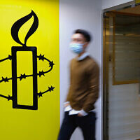 Illustrative: A man walks past the logo of the Amnesty International at its office in Hong Kong, October 25, 2021. (AP Photo/Vincent Yu)