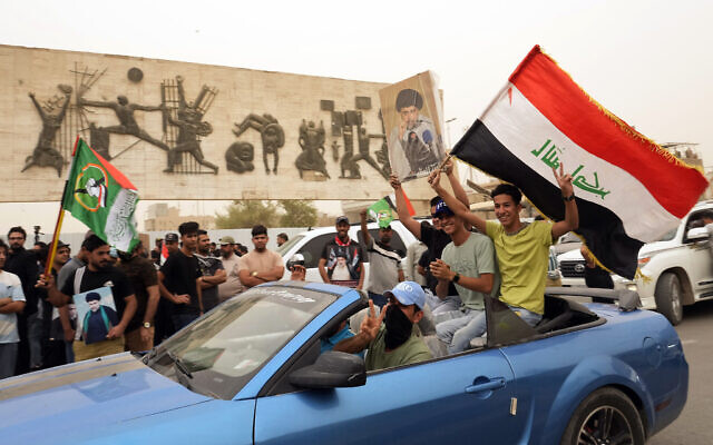 Followers of Shiite cleric Muqtada al-Sadr hold a poster with his photo and wave an Iraqi flag as they celebrate the passing of a law criminalizing the normalization of ties with Israel, in Tahrir Square, Baghdad, Iraq, May 26, 2022. (AP Photo/Hadi Mizban)