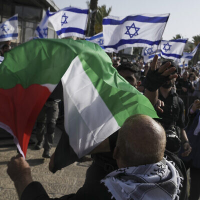 A man waves a Palestinian flag as Israelis mark Jerusalem Day outside the capital's Old City on May 29, 2022. (AP Photo/Mahmoud Illean)