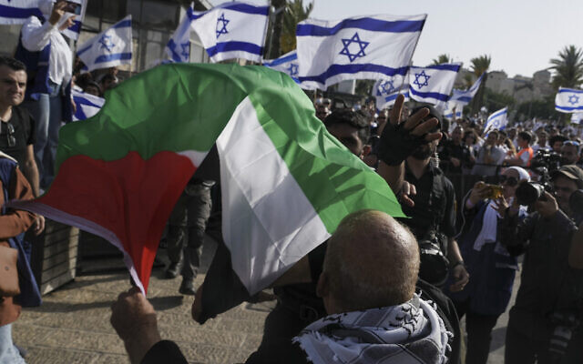 A man waves a Palestinian flag as Israelis mark Jerusalem Day outside the capital's Old City on May 29, 2022. (AP Photo/Mahmoud Illean)