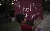 Eight-year-old Jeremiah Lennon picks at a sign that reads "Uvalde Strong" which he helped decorate and stuck on an electric pole in front of his home on May 28, 2022, in Uvalde, Texas. Lennon was in a classroom just next to the room where three of his friends were slain when a gunman killed 19 students and two teachers at Robb Elementary. (AP Photo/Wong Maye-E, File)
