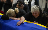The mother, right, and sister of Army Col. Oleksander Makhachek mourn over the coffin with his remains during a funeral service in Zhytomyr, Ukraine, June 3, 2022. (Natacha Pisarenko/AP)