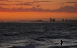 A man wades into the ocean at sunset on June 22, 2021, in Newport Beach, California. (Jae C. Hong/AP)