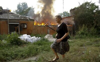 A woman runs from a house that's on fire after shelling in Donetsk, on the territory which is under the Government of the Donetsk People's Republic control, eastern Ukraine, June 3, 2022. (AP Photo/Alexei Alexandrov)