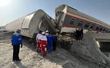 In this photo provided by Iranian Red Crescent Society, rescuers work at the scene where a passenger train partially derailed near the desert city of Tabas in eastern Iran, June 8, 2022. (Iranian Red Crescent Society via AP)