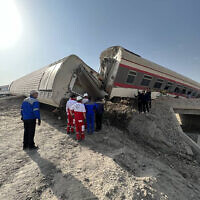 In this photo provided by Iranian Red Crescent Society, rescuers work at the scene where a passenger train partially derailed near the desert city of Tabas in eastern Iran, June 8, 2022. (Iranian Red Crescent Society via AP)