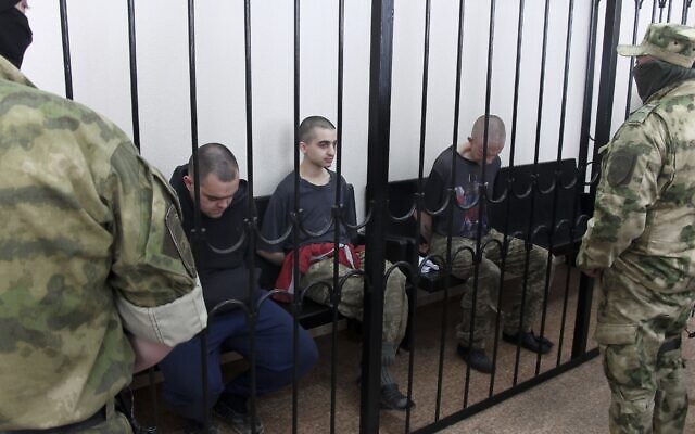Two British citizens Aiden Aslin, left, and Shaun Pinner, right, and Moroccan Saaudun Brahim, center, sit behind bars in a courtroom in Donetsk, in the territory which is under the Government of the Donetsk People's Republic control, eastern Ukraine, Thursday, June 9, 2022.(AP Photo)