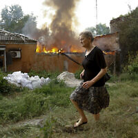 A woman runs from a house that's on fire after shelling in Donetsk, on the territory which is under the Government of the Donetsk People's Republic control, eastern Ukraine, Friday, June 3, 2022.  (AP Photo/Alexei Alexandrov, file)