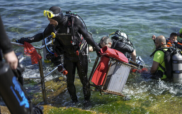 A scuba-diving volunteer comes out of the water holding a chair he collected during World Ocean Day event in the Mediterranean ancient Caesarea's Roman-period port, Israel, June 10, 2022. (AP Photo/Ariel Schalit)