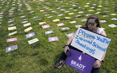 A woman listens to speakers during a rally near Capitol Hill in Washington, June 10, 2022, urging Congress to pass gun legislation. On display next to her are school notebooks representing children who have died from gun violence. (Susan Walsh/AP)