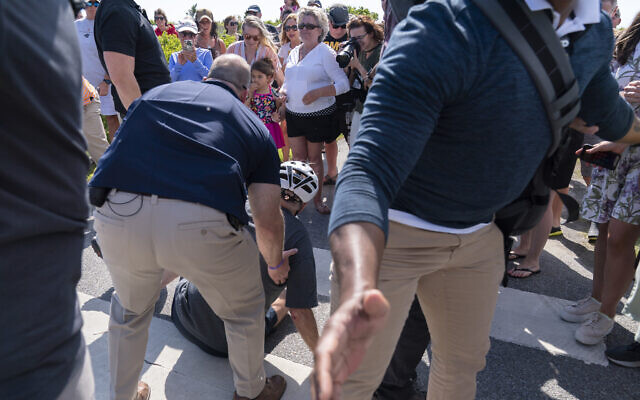 US President Joe Biden is helped by Secret Service agents after he fell trying to get off his bike to greet a crowd on a trail at Gordons Pond in Rehoboth Beach, Del., June 18, 2022. (AP Photo/Manuel Balce Ceneta)
