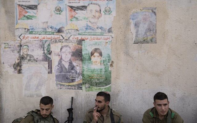 Israeli soldiers rest next to a faded posters slain Palestinian fighters, during an urban warfare exercise at an army training facility, in Tzeelim army base, southern Israel, Jan. 4, 2022. (Oded Balilty/AP)